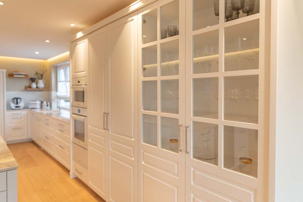 Küchenfront in weiß mit Glasvitrine und integriertem Backofen.